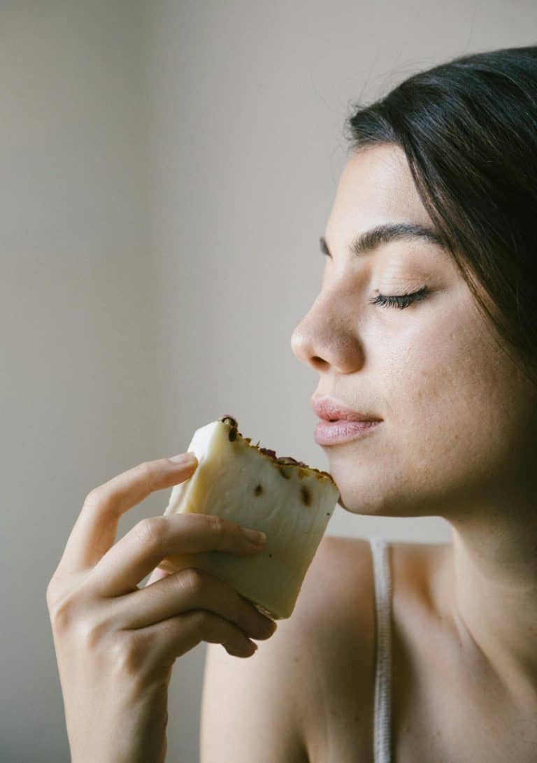 Profile of a woman enjoying the scent of handmade soap in a calm studio setting.