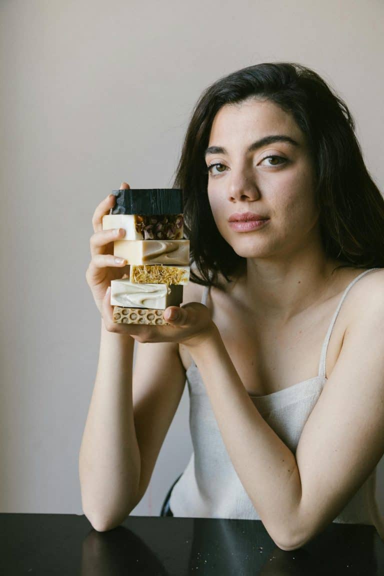 Young woman in Istanbul showcasing a stack of handmade artisan soaps indoors.